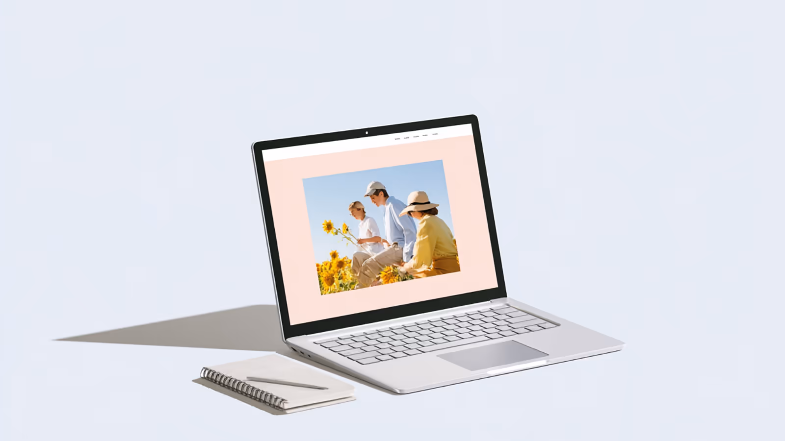 Aufgeklappter Laptop auf hellem Grund, auf dem Bildschirm eine Website mit einem Foto von drei Menschen in einem Sonnenblumenfeld